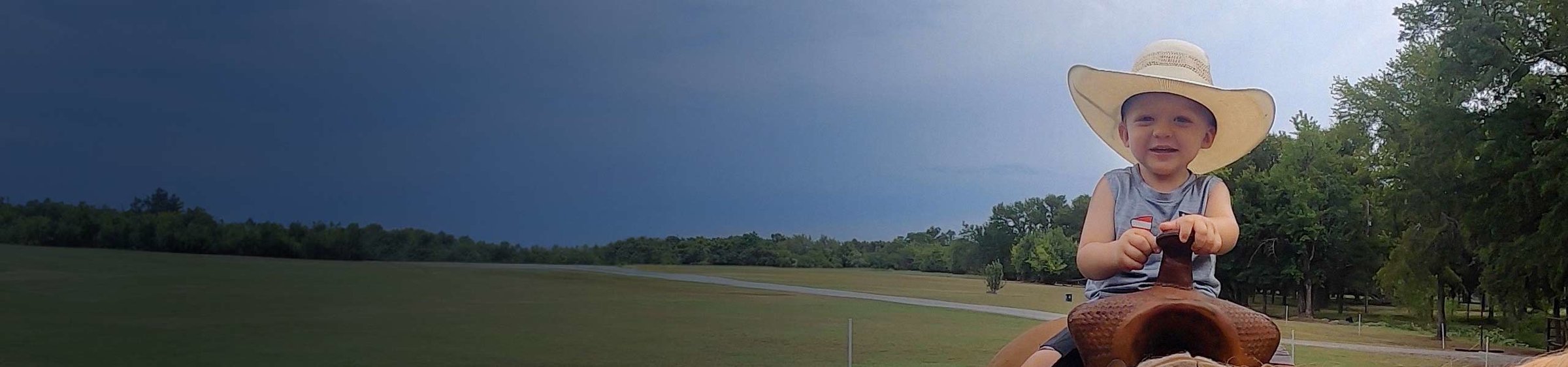 Brady, a child with SMA, in an oversized cowboy hat, horseback riding