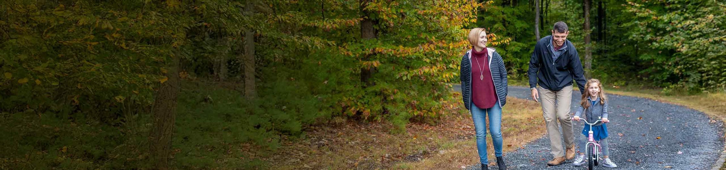 Evelyn, a child with SMA, riding a bike as her parents, Elena and Milan, walk by her side