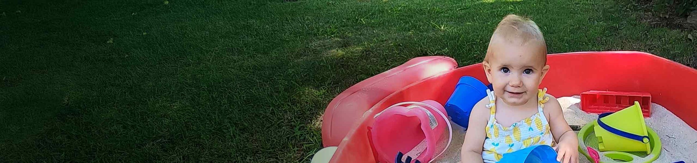 Lucy, a child with SMA, smiling as she plays in a sandbox