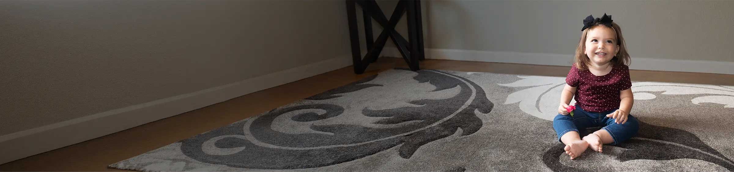 Natalie, a child with SMA, sitting alone on a rug