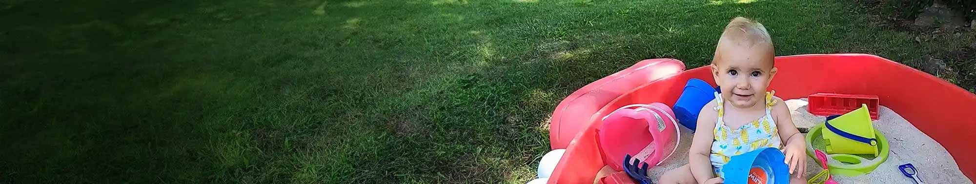 Lucy, a child with SMA, smiling as she plays in a sandbox