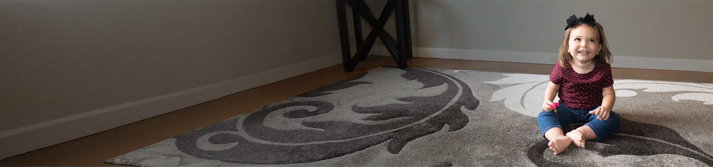 Natalie, a child with SMA, sitting alone on a rug