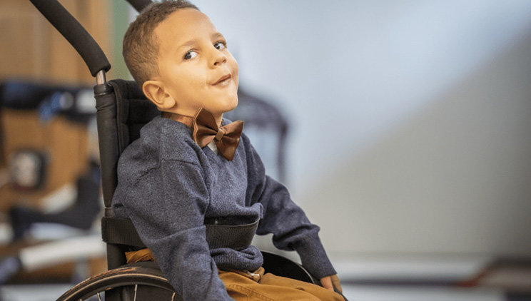 Malachi, a child with SMA, in a wheelchair staring off into the distance